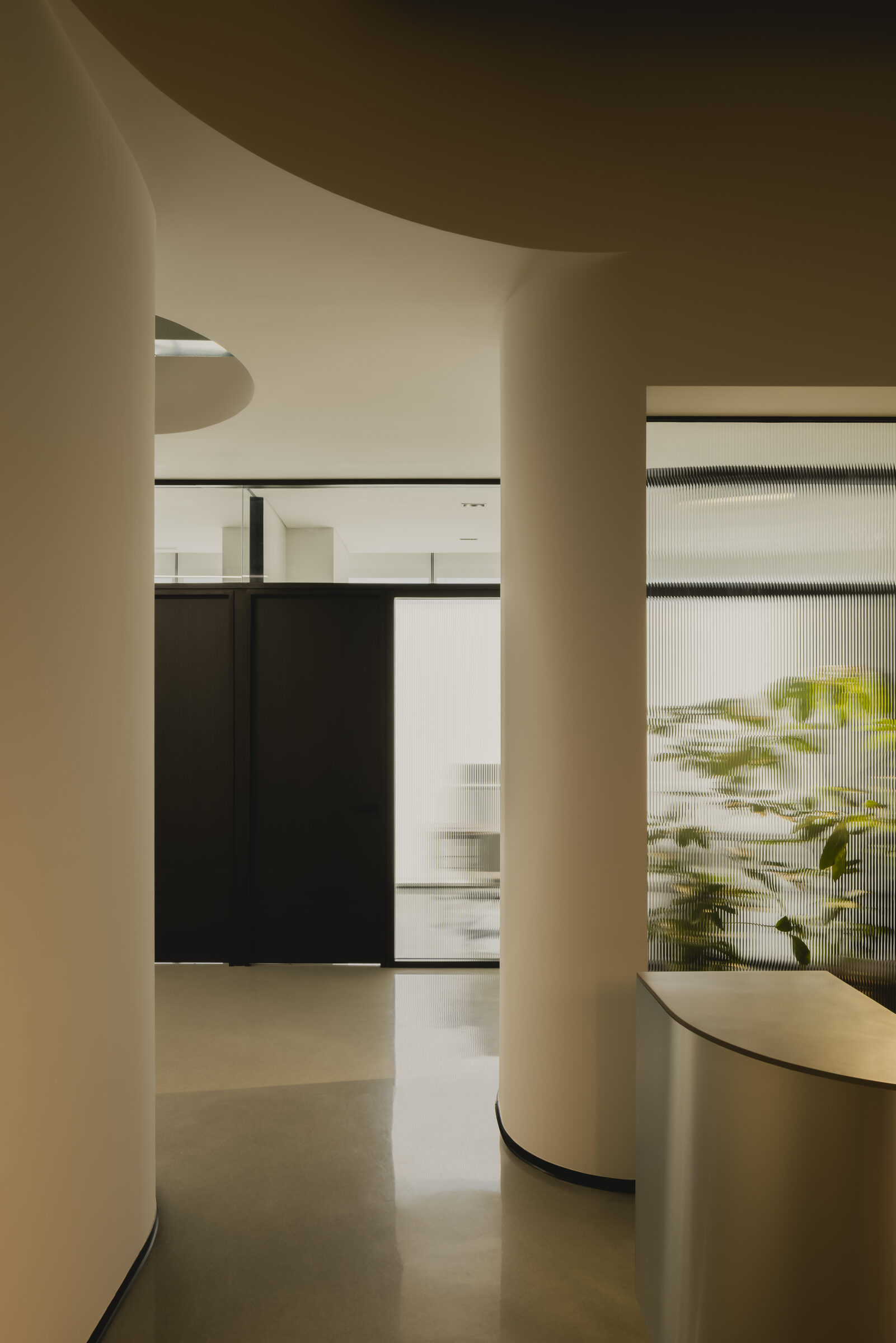 Vestíbulo residencial con carpintería integral y muros curvos