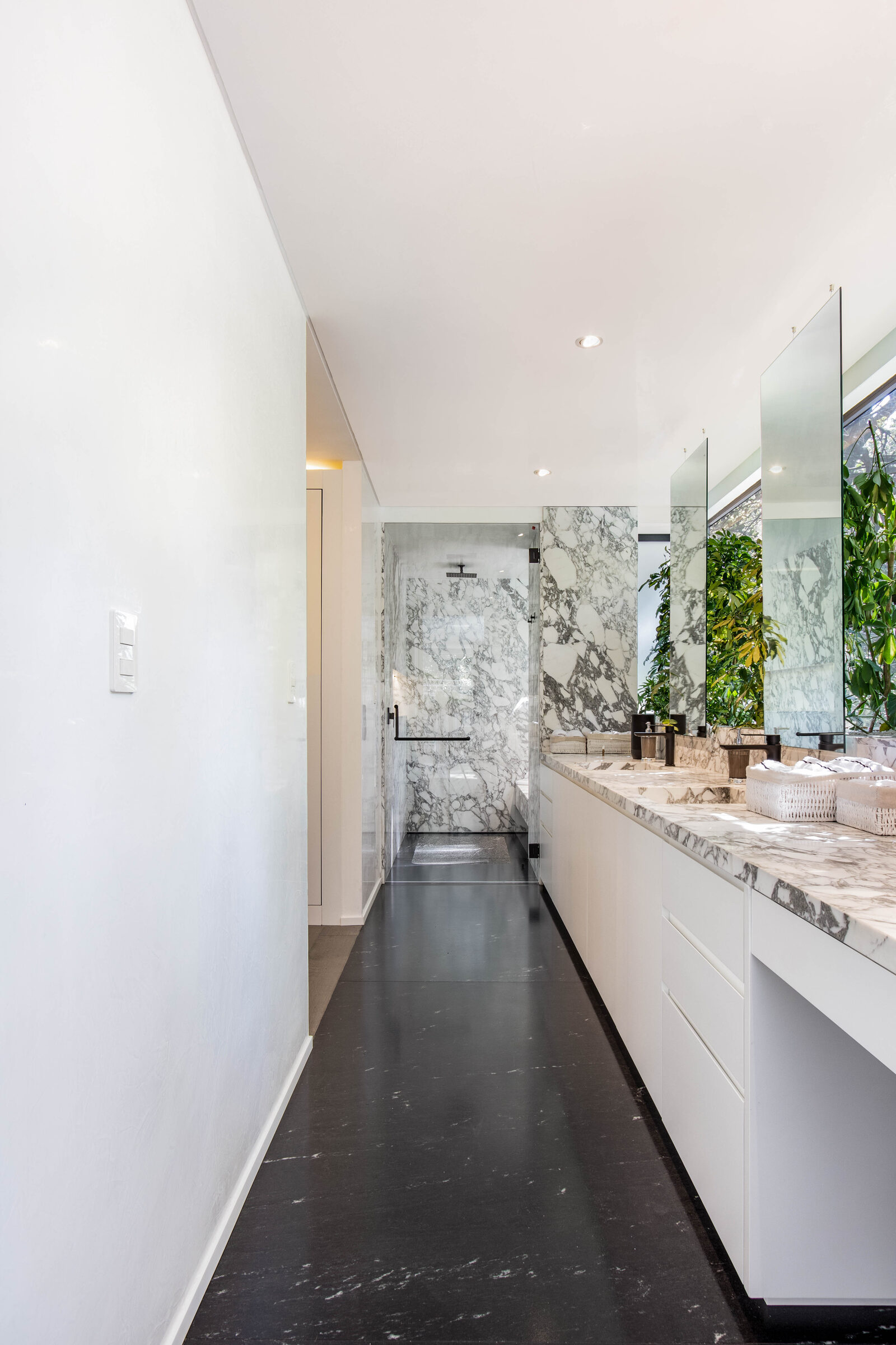 Baño con carpintería integral, mármol y acabados en negro mate